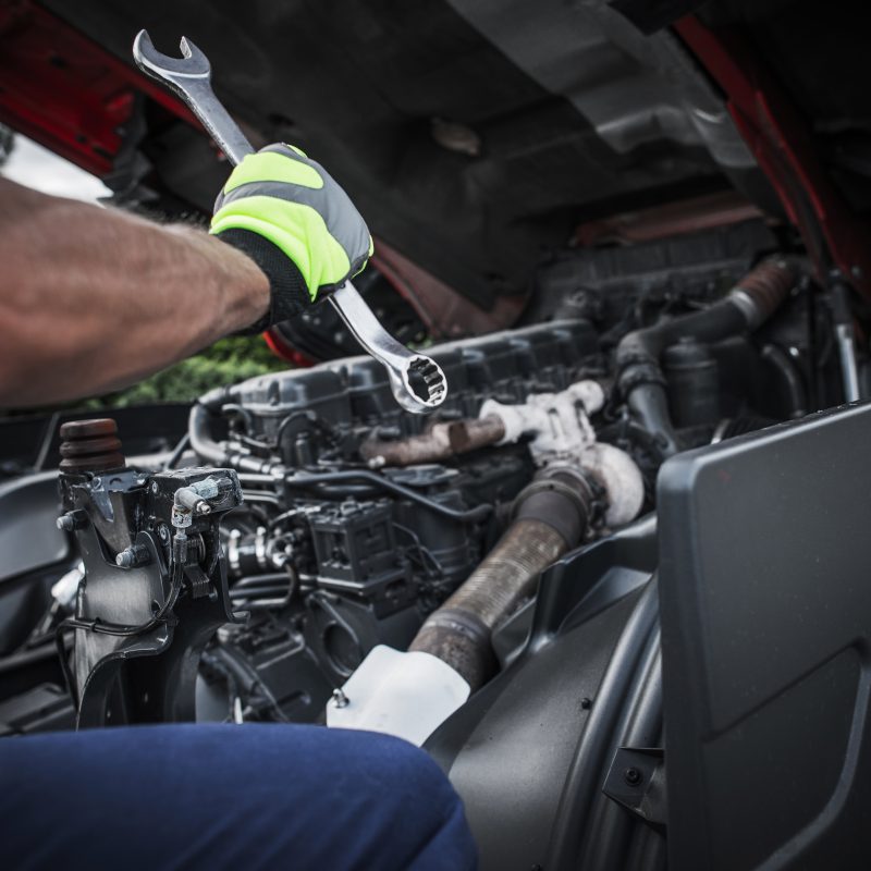 Caucasian Truck Mechanic Repairing Semi Truck Engine.