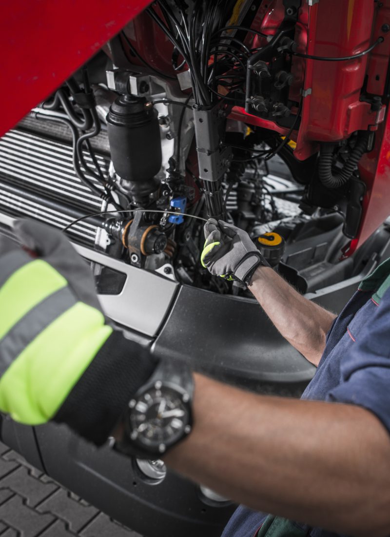 Truck Service Oil Level Check by Caucasian Worker Technician. Semi Truck Maintenance.